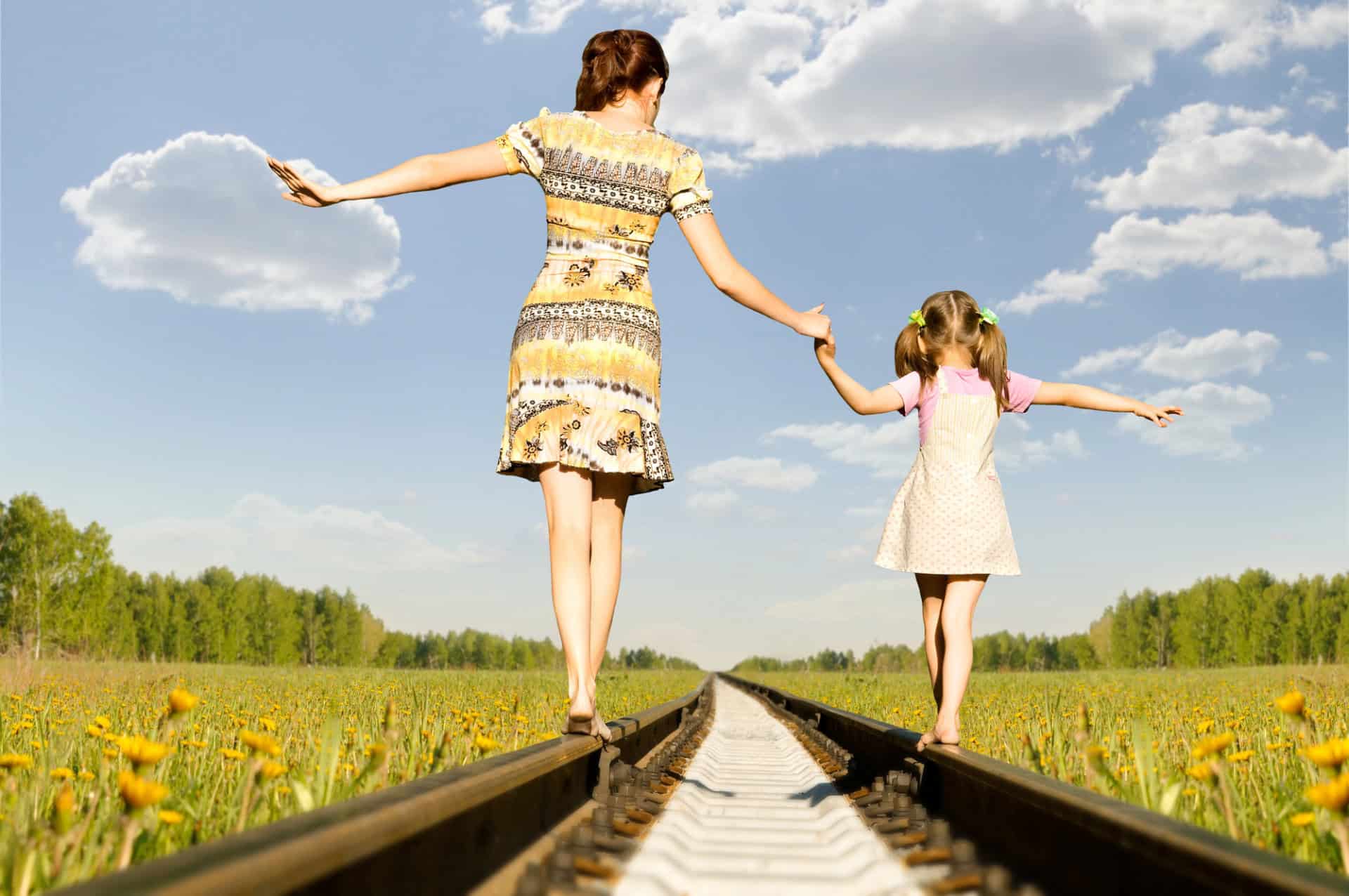 Mom and daughter walk together on railroad tracks
